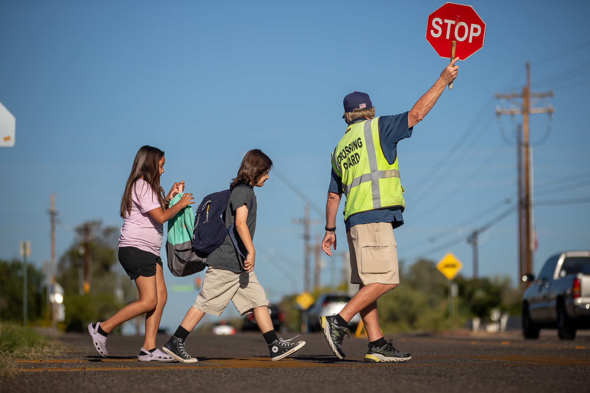 Crossing Guard holding up 'Stop" sign for student to cross the street