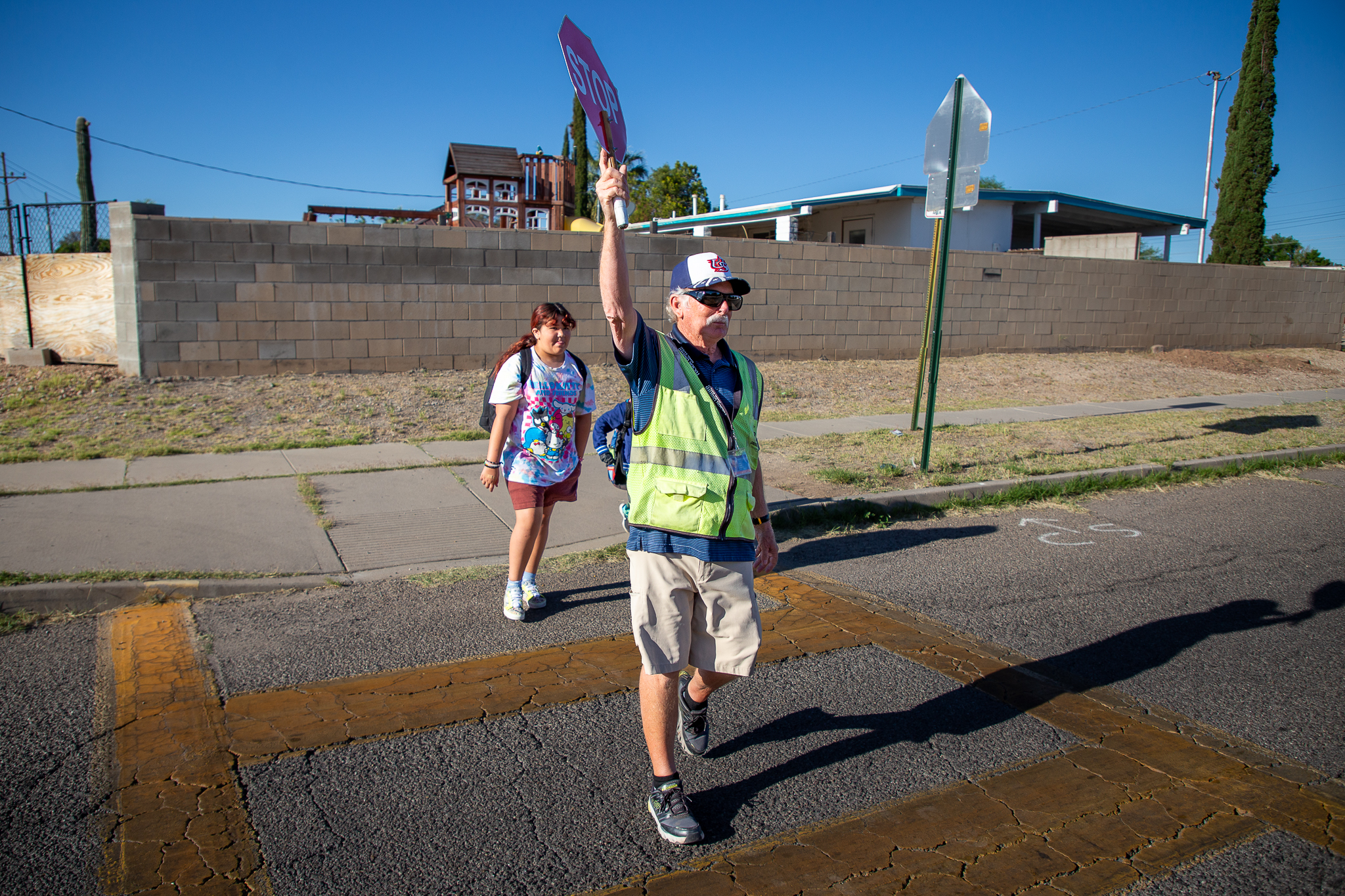 Crossing Guard Steve walking and raising the "stop" sign for student to cross the street