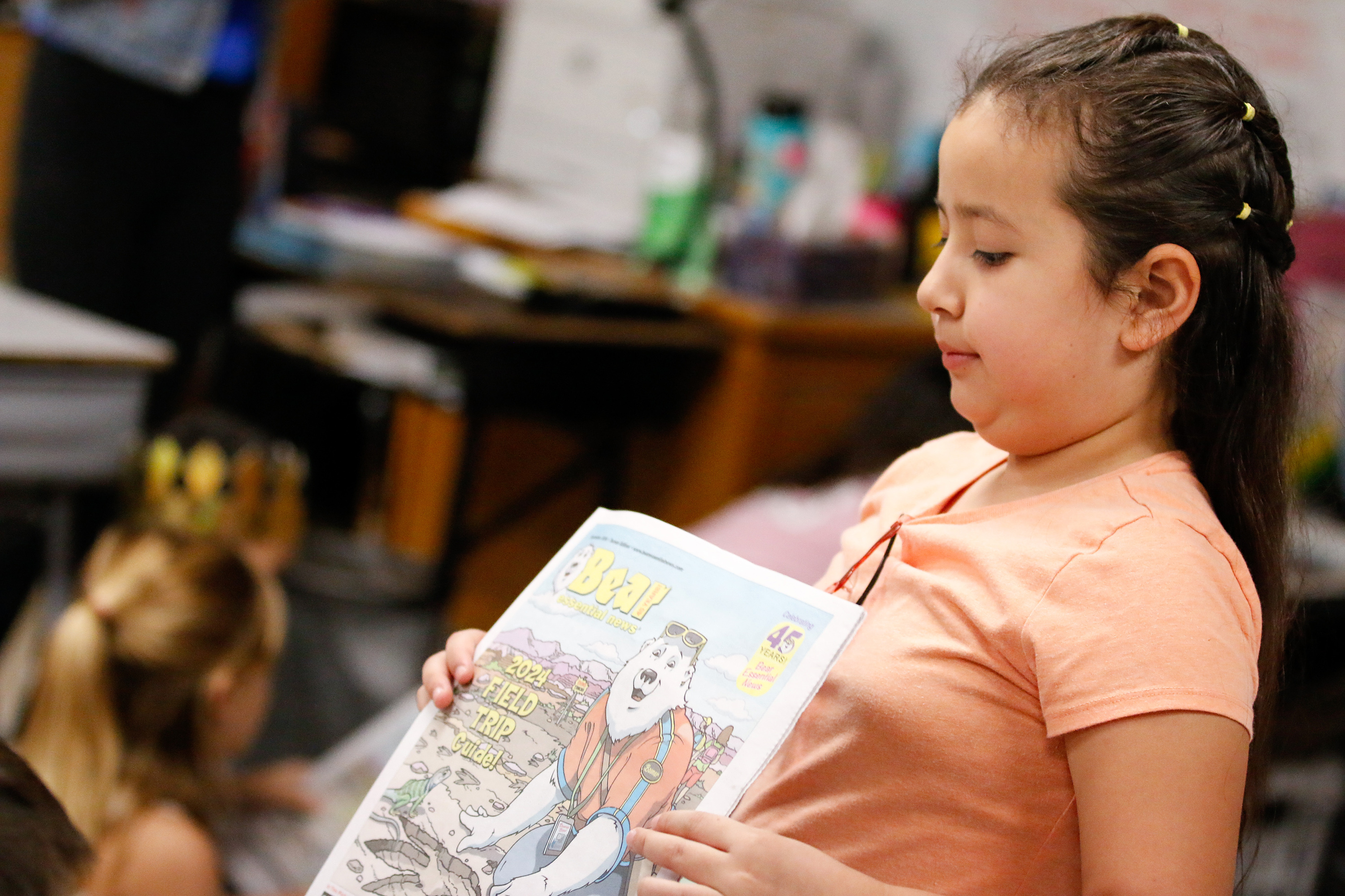 A girl holds up a copy of Bear Essential News