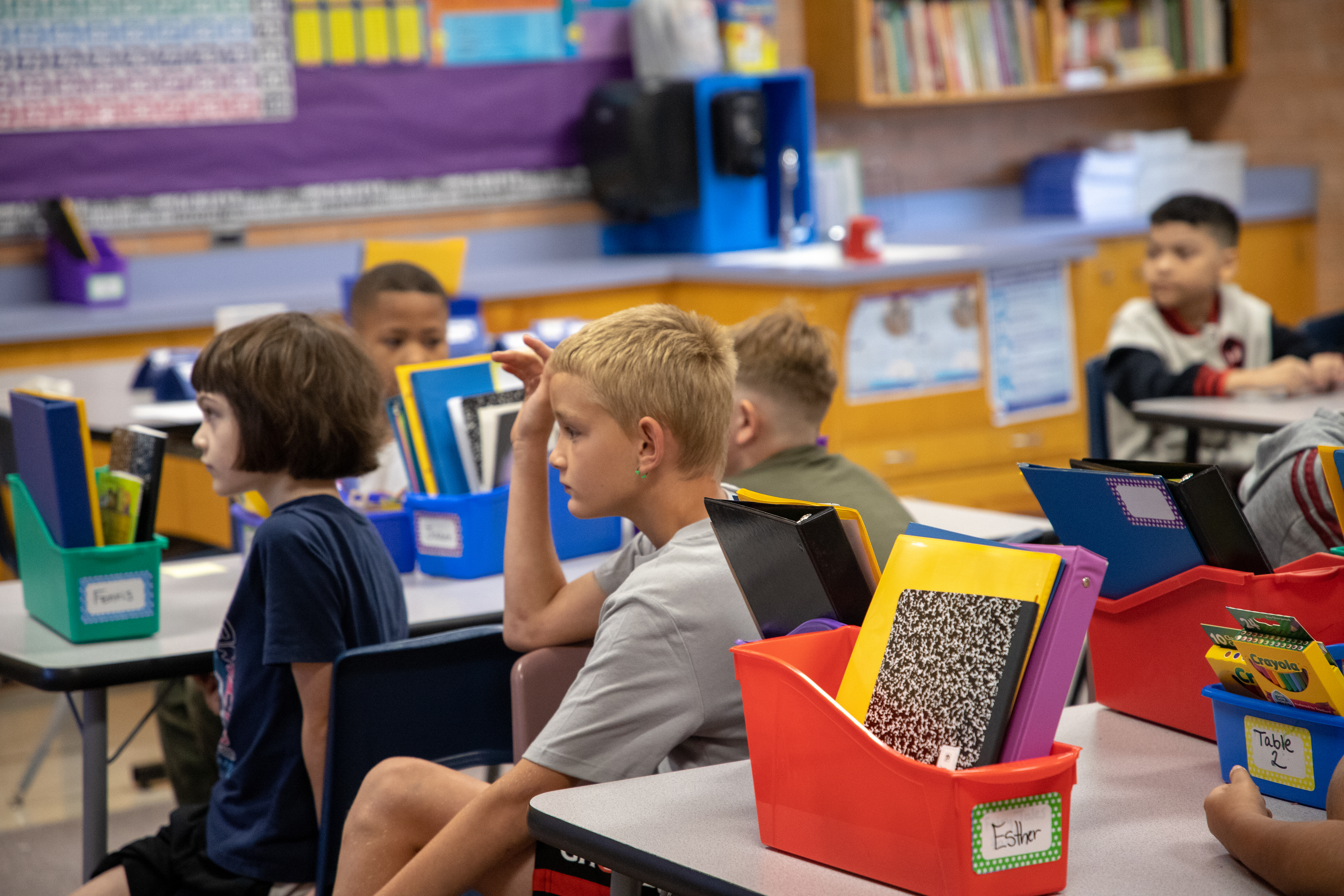 A little boy raises his hand on the first day of shcool