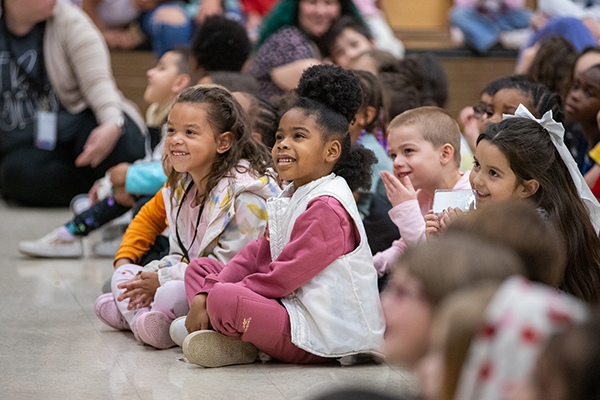 Students smile as they sit on the cafeteria floor watching a yo-yo performance
